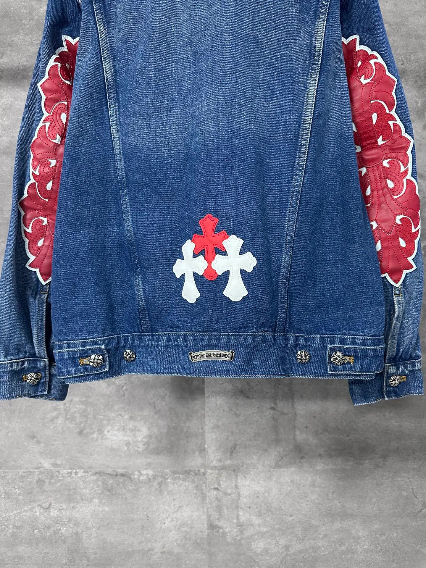P720 CHrome Hearte cross patchwork leather denim jacket size: S M L Design details: the visual fantasy of Gothic symbols, the multi-dimensional expression of the cross totem: the red and white contrasting cross patches are staggered on the chest and back, making the brand more recognizable; the hollow cross pattern leather splicing on the sleeves combines the mystery of religious symbols with the punk-style deconstructed design. Every detail tells the dark aesthetics of Crowe's heart. Retro distressing with denim texture: Selected denim fabrics are treated with distressing techniques to show natural fading and texture, which not only retains the retro accent of denim items, but also adds a casual sense to the overall look. The ingenuity of hardware and tailoring: The metal buttons and hardware all have Croxin's iconic pattern, which shines exquisitely under the refraction of light; the neat tailoring of the classic denim jacket is suitable for a variety of wearing scenarios, and can create a strong personal style whether it is layered or worn alone. Croxin's denim jacket is not only a piece of clothing, but also a style badge that highlights unique aesthetics and rebellious attitude. For those who pursue individuality, they can leave their own hardcore mark in the fashion field.